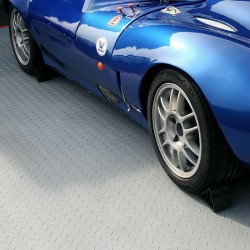 Photo d'un sol de garage fait de dalles PVC encastrables Daytona gris clair avec une voiture bleue garée
